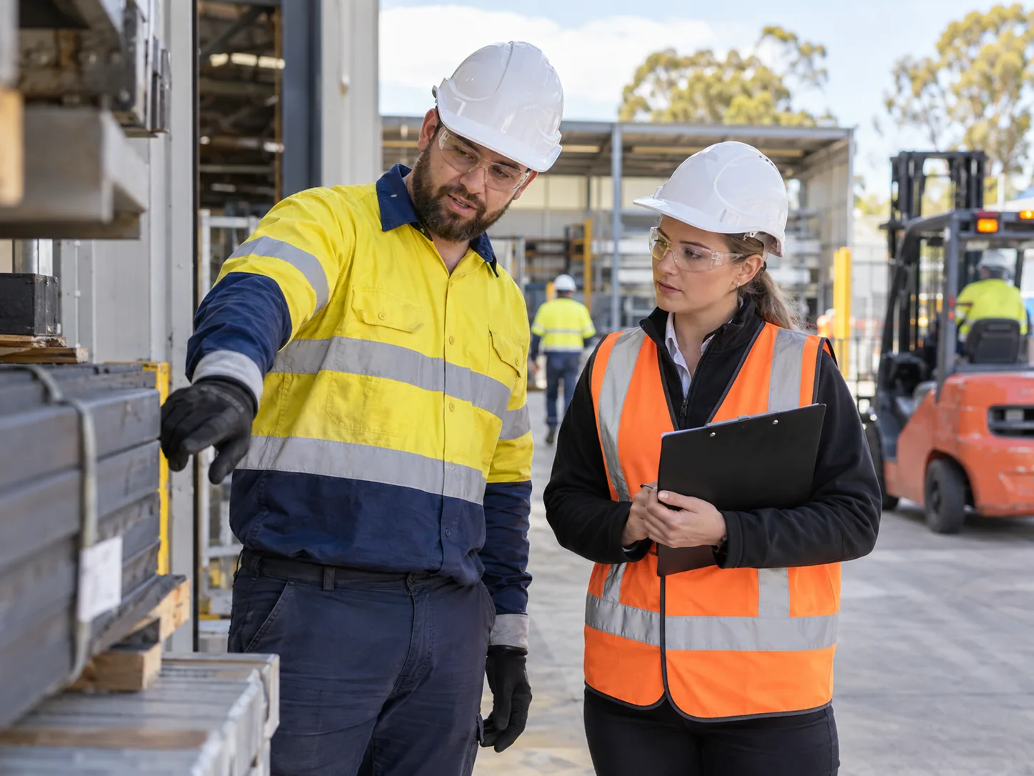 Two workers in protective equipment reviewing a workplace hazard and discussing a risk control.